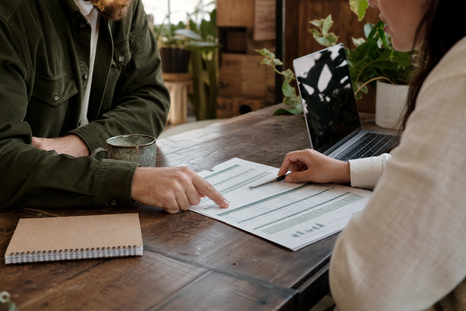 Twee ondernemers bespreken samen een kasstroomoverzicht aan een houten tafel